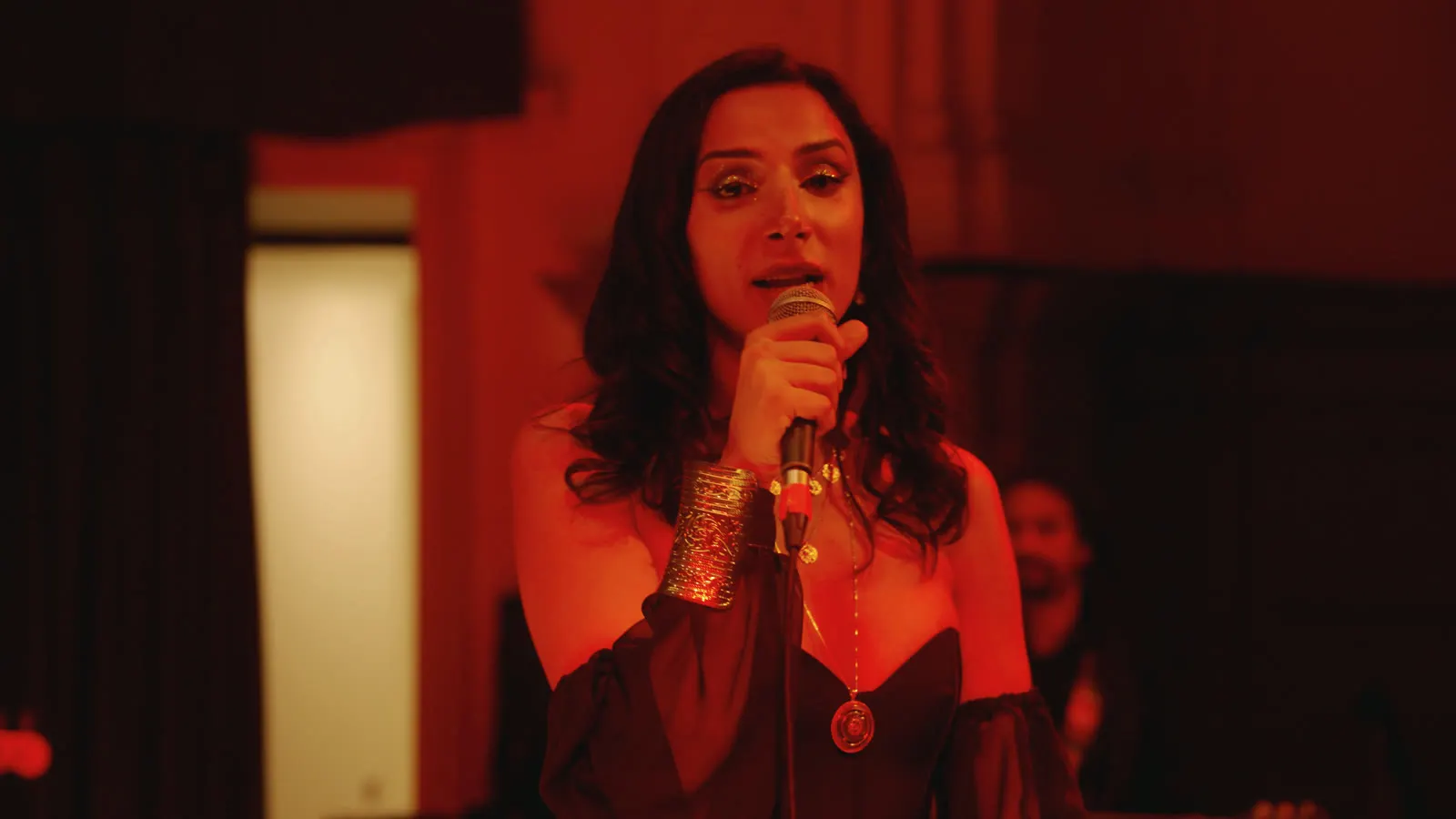 Portrait of Sura at the microphone in warm red light