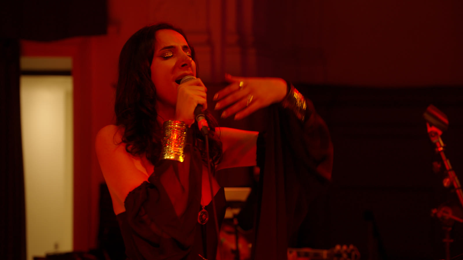 Sura at the microphone, engraved cuff catching the light