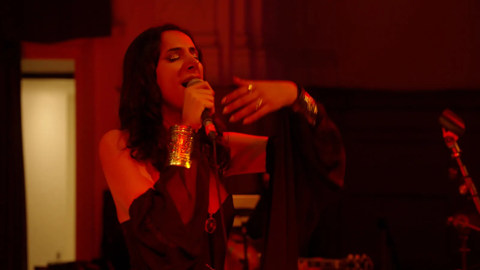 Sura at the microphone, engraved cuff catching the light